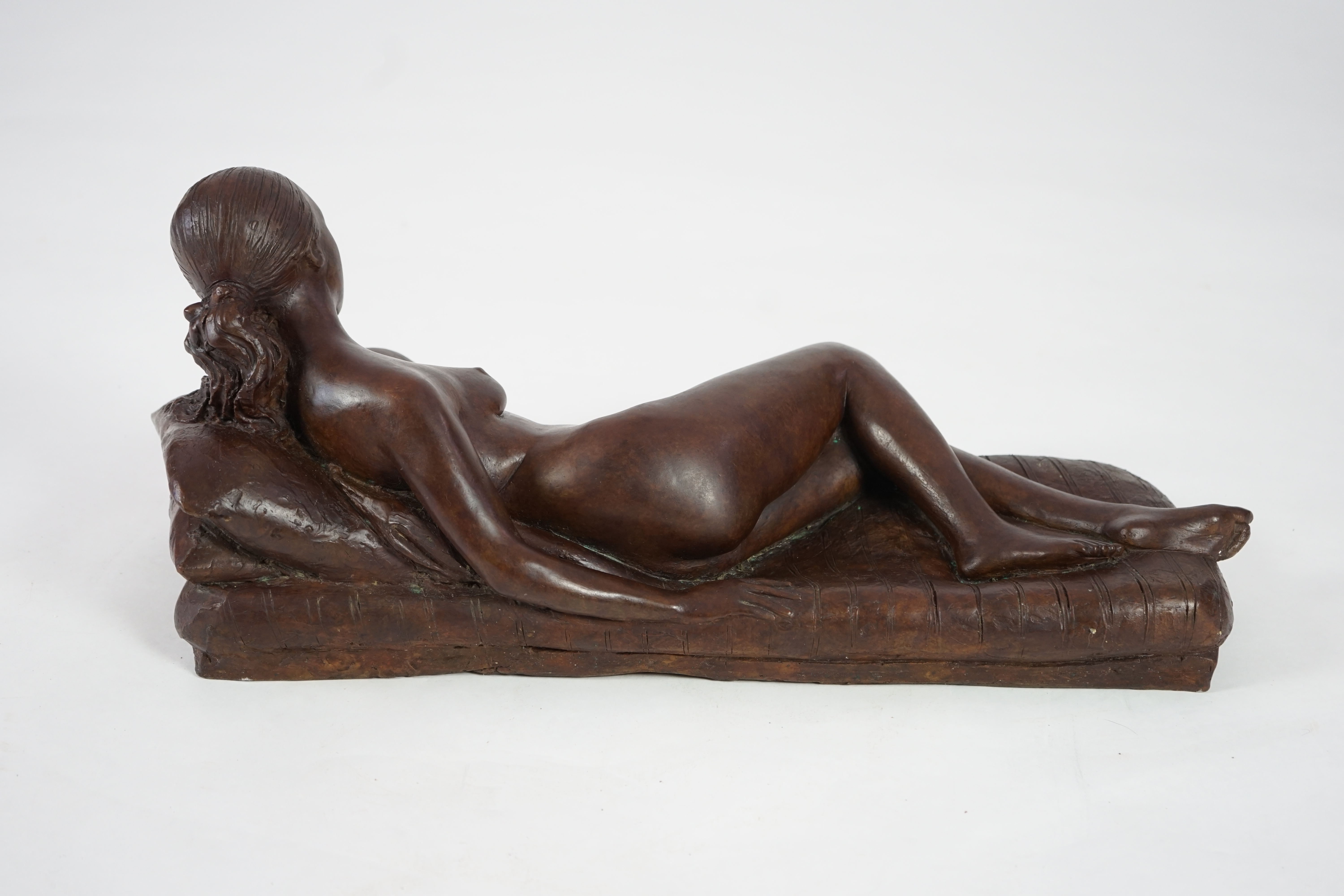 James Butler (1931-2022). A bronze figure of a female nude reclining upon cushions